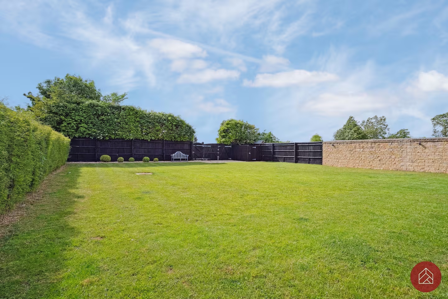 Landscaped garden enclosed by mature hedging and a stone wall